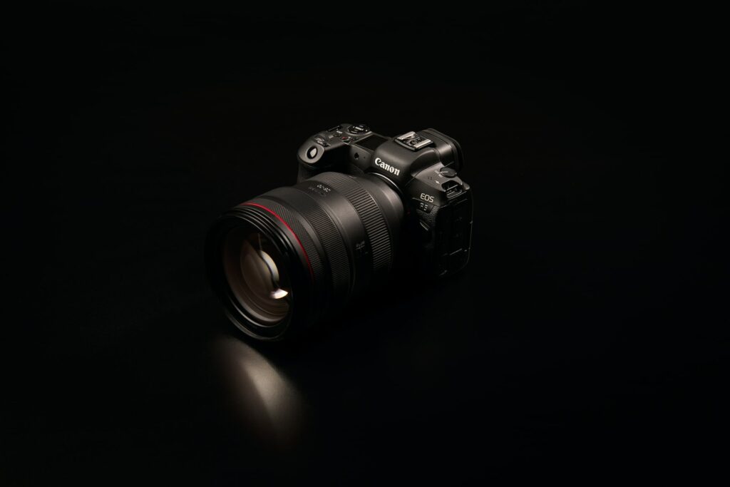 A black Canon SLR camera on a black surface and black background