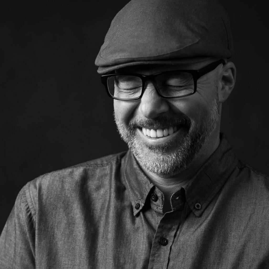 Black and white image of Scott Basile wearing a beret and glasses