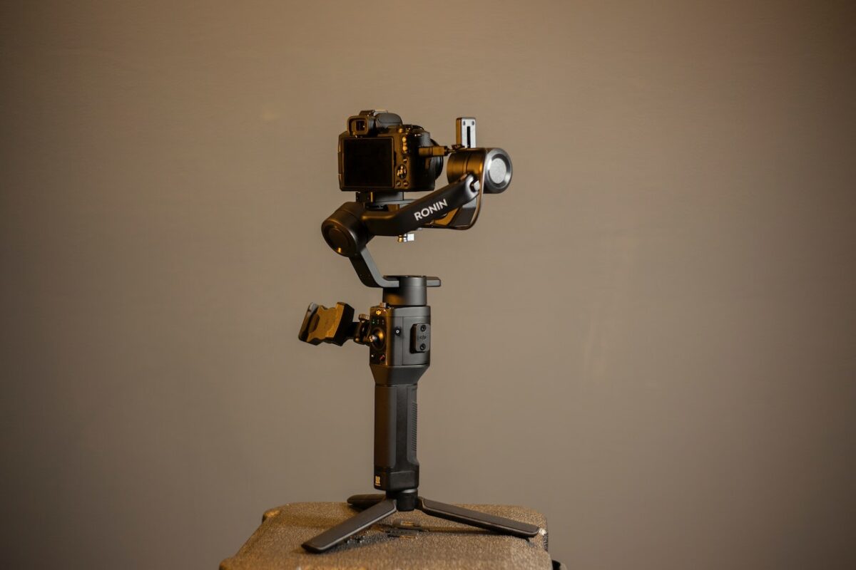 A black Ronin gimbal with a black DSLR camera was placed on a chair