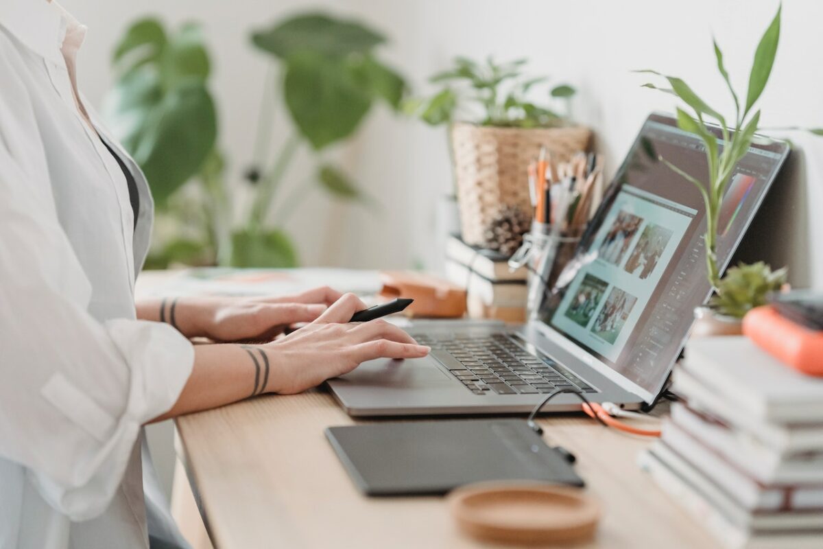 A woman in long sleeves using a silver laptop in retouching the photos