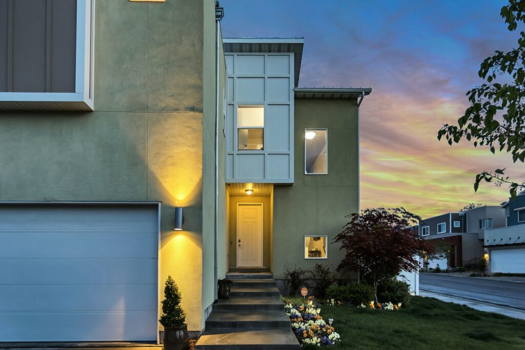 A house with a white garage door, a well-kept lawn, and yellow outdoor lamps in a modern neighborhood