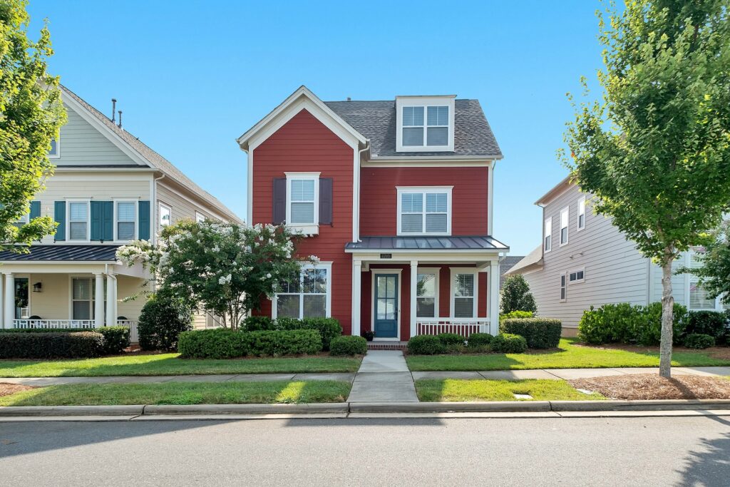 A red concrete house with a well-maintained front yard near tall green trees