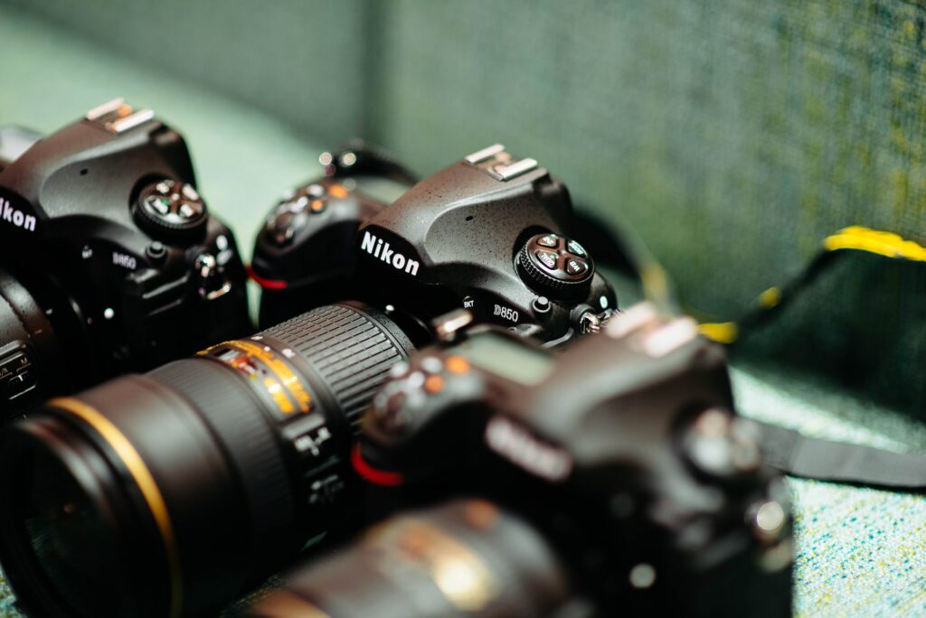 Close-up of three black Nikon DSLR cameras placed on a colored mat