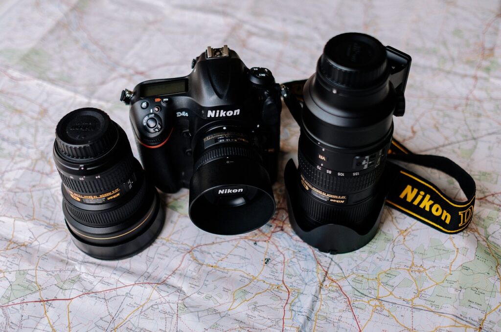 A Black Nikon DSLR camera and two lenses were placed on top of a big map
