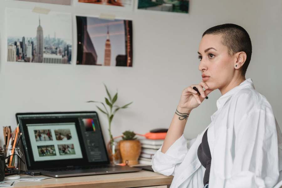 Woman pensive, as she sits in front of her laptop