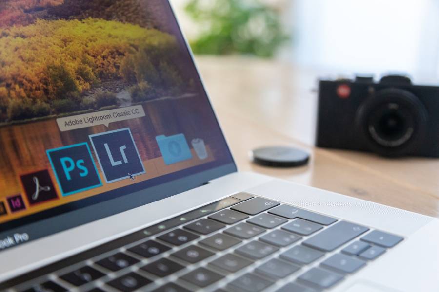 Camera beside a laptop with Photoshop and Lightroom software