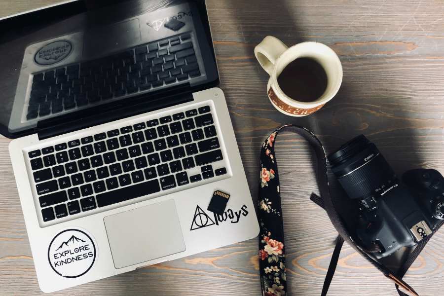 A cup of coffee and a camera beside a laptop