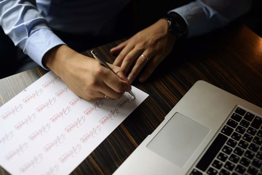 Person practicing their signature on a piece of paper
