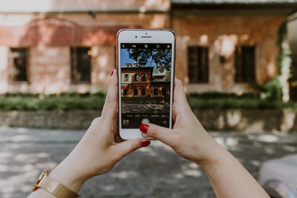 Person taking a photo of a house using an iPhone