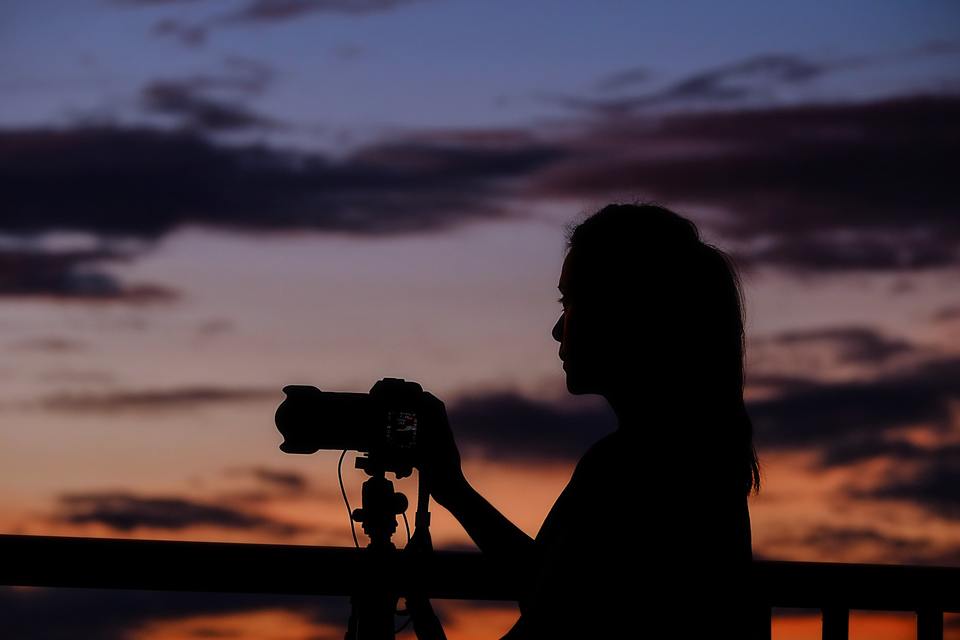Woman shooting with camera during twilight