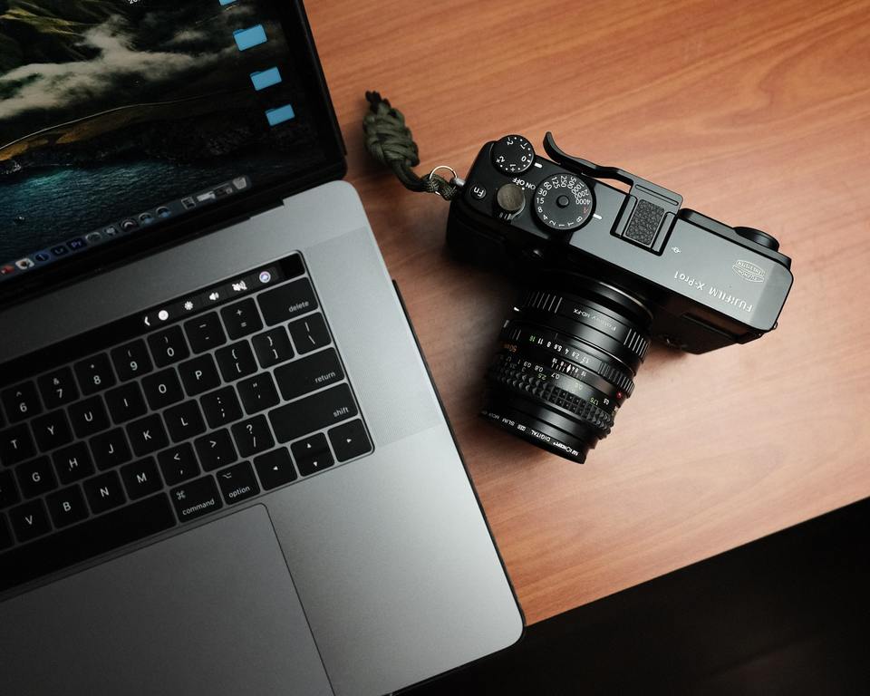 Laptop and camera on a wooden desk