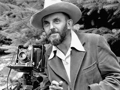A black and white image of Ansel Adams while using a camera